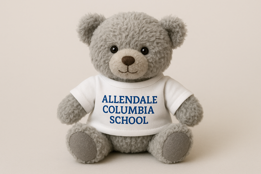 small gray teddy bear wearing a white t-shirt that says "Allendale Columbia School" in blue lettering
